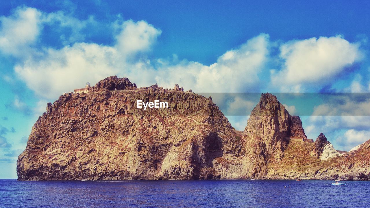 Scenic view of rock formations by sea against sky