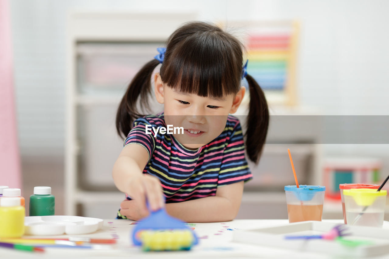 Young girl decorating hand made craft for homeschooling