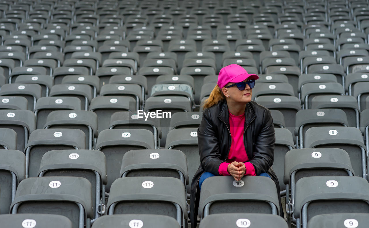 Front view of woman with sunglasses sitting on seat at stadium