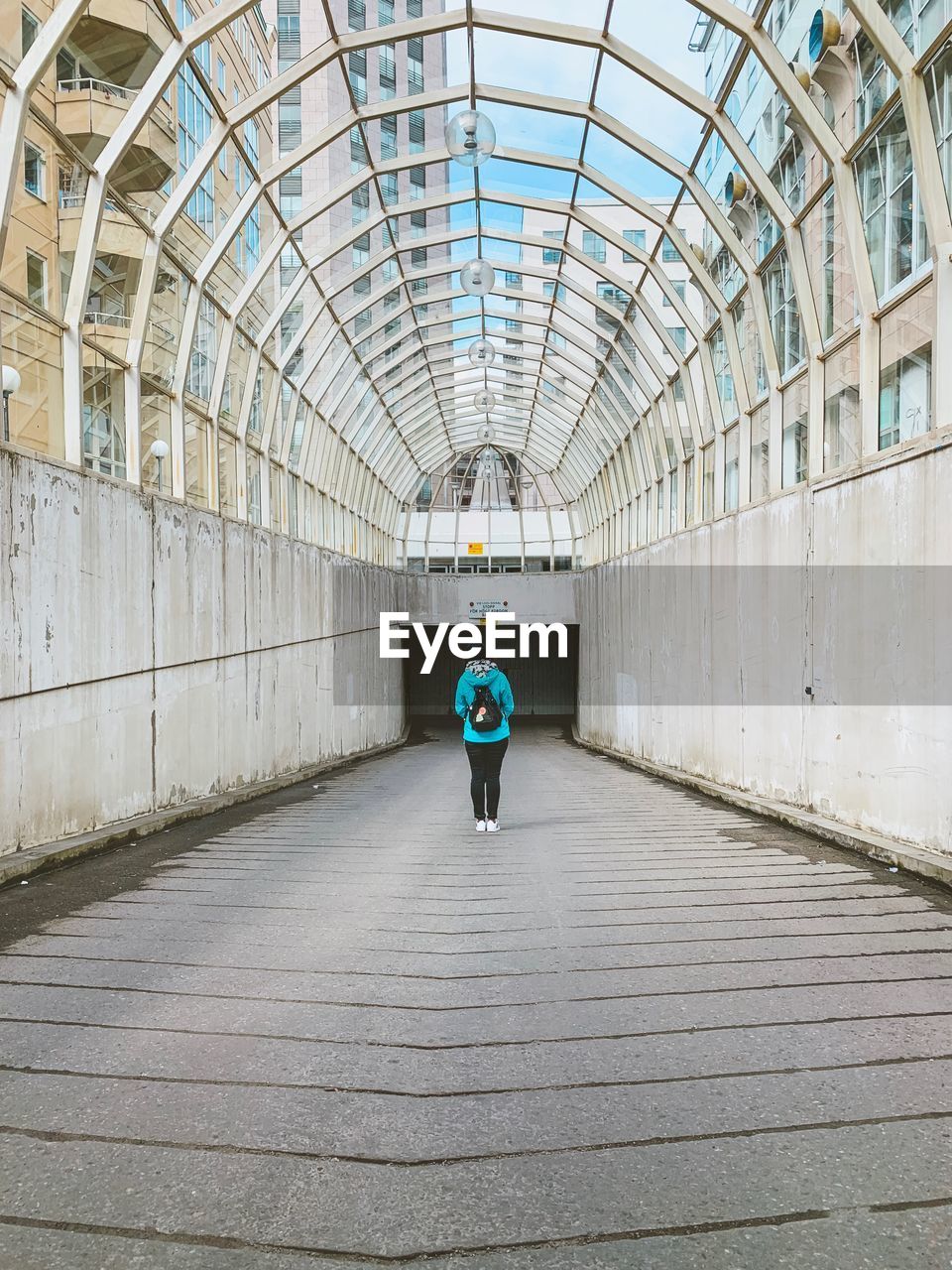 REAR VIEW OF MAN WALKING ON TUNNEL