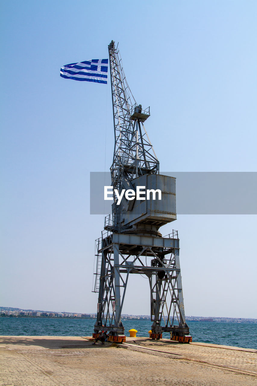 Thessaloniki, greece, july 15, 2021. greek flag on a crane in the port of thessaloniki