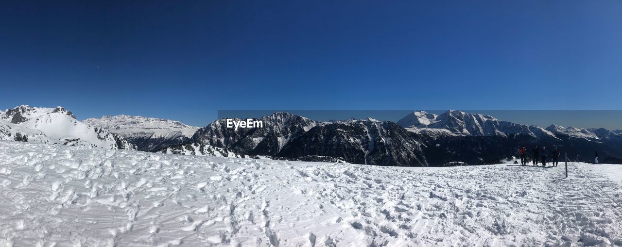 Scenic view of snowcapped mountains against clear blue sky