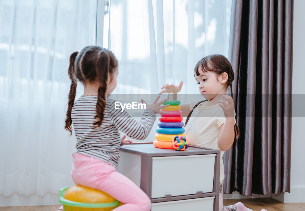 Sisters playing with multi colored toys at home