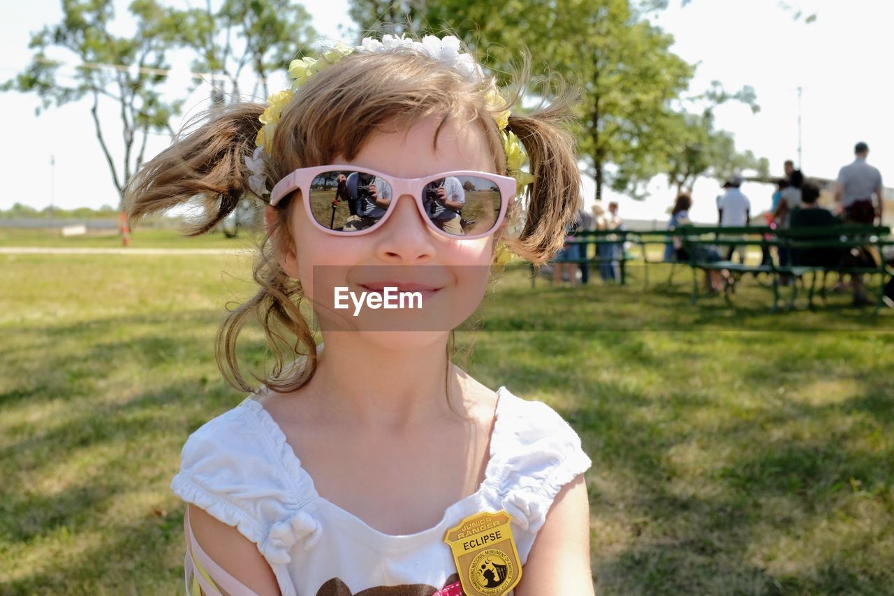 PORTRAIT OF SMILING GIRL WEARING SUNGLASSES OUTDOORS