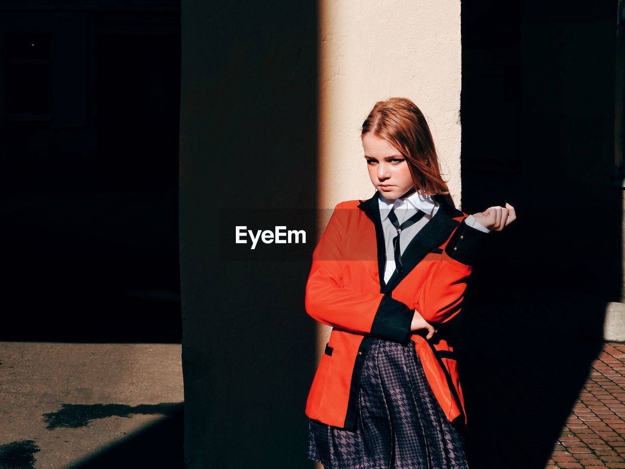Young woman looking away while standing against wall