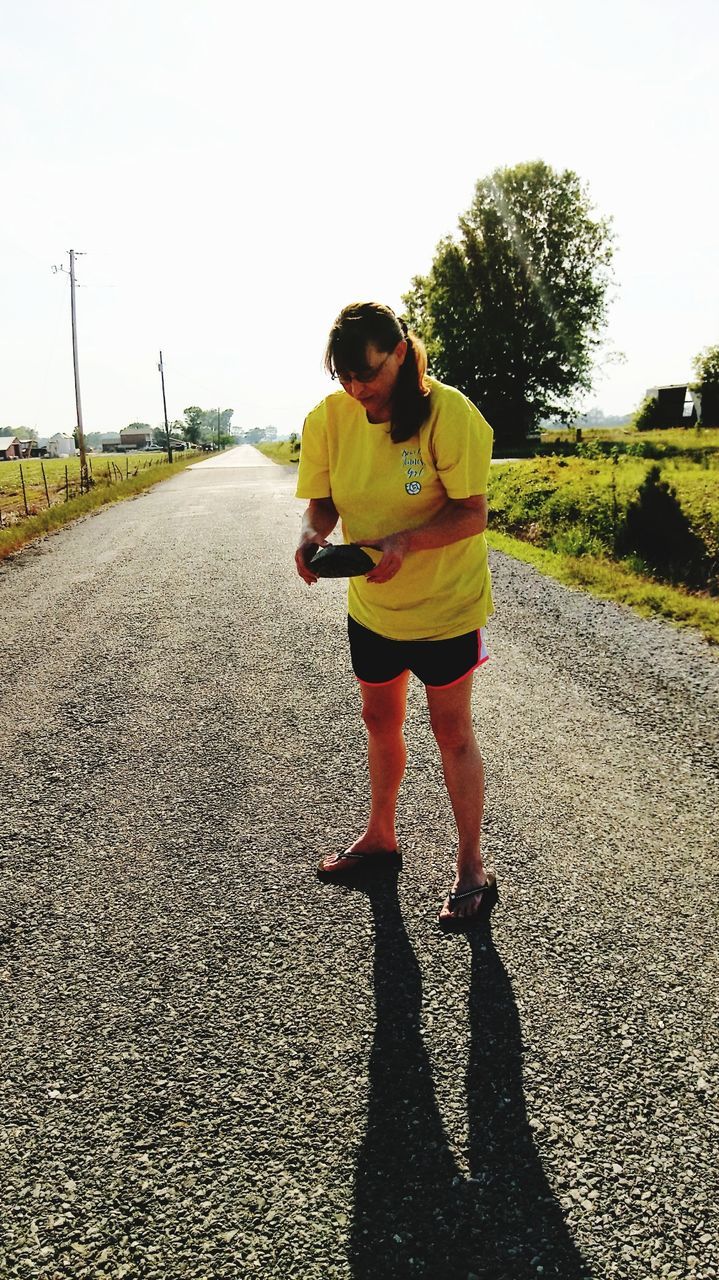 FULL LENGTH OF MAN STANDING ON ROAD AGAINST TREES