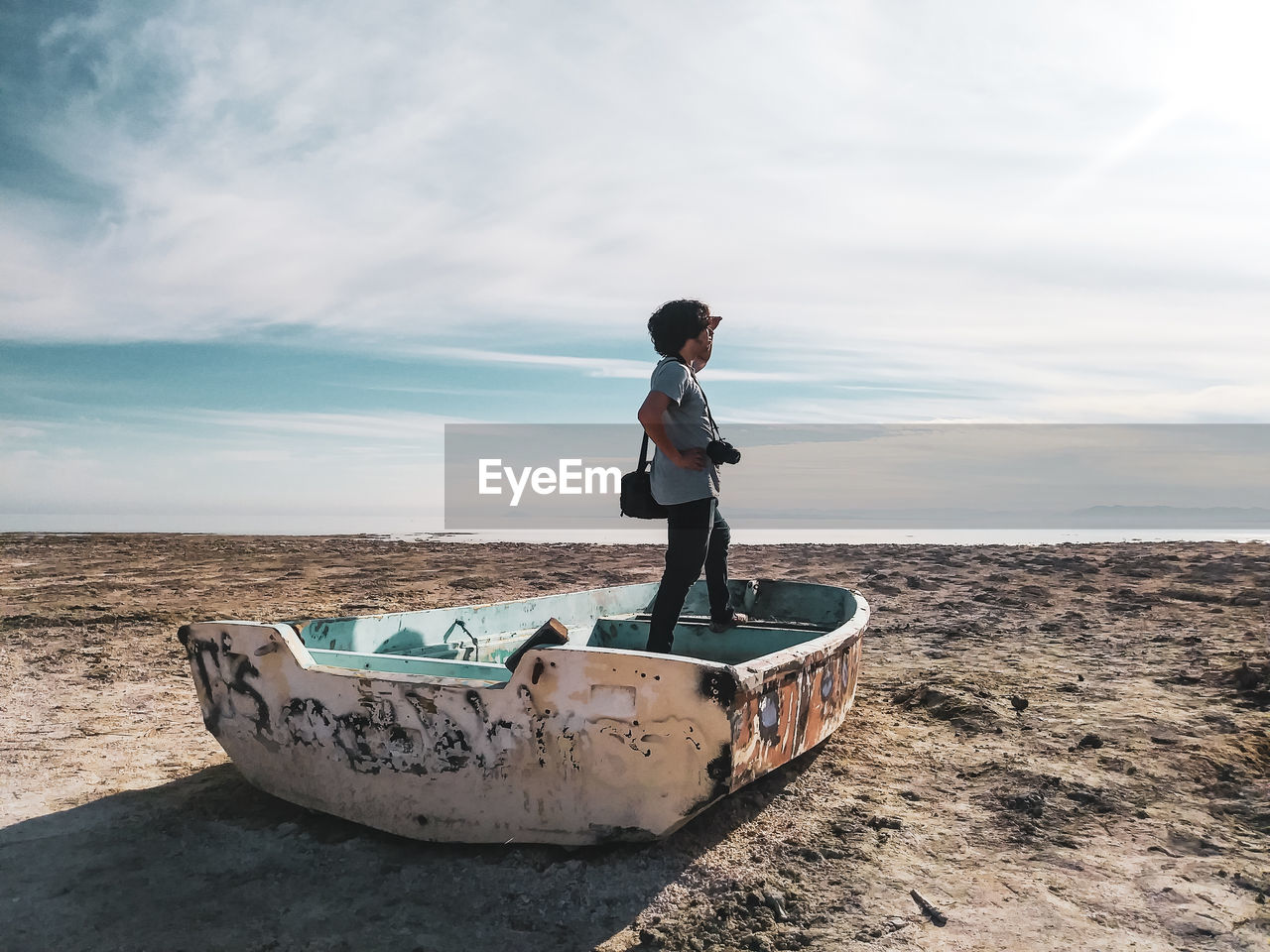 Man standing in boat moored at beach against sky