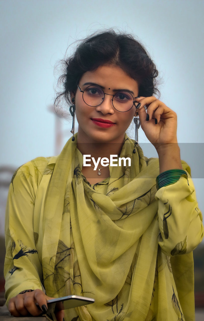 Young woman wearing glasses while standing against wall