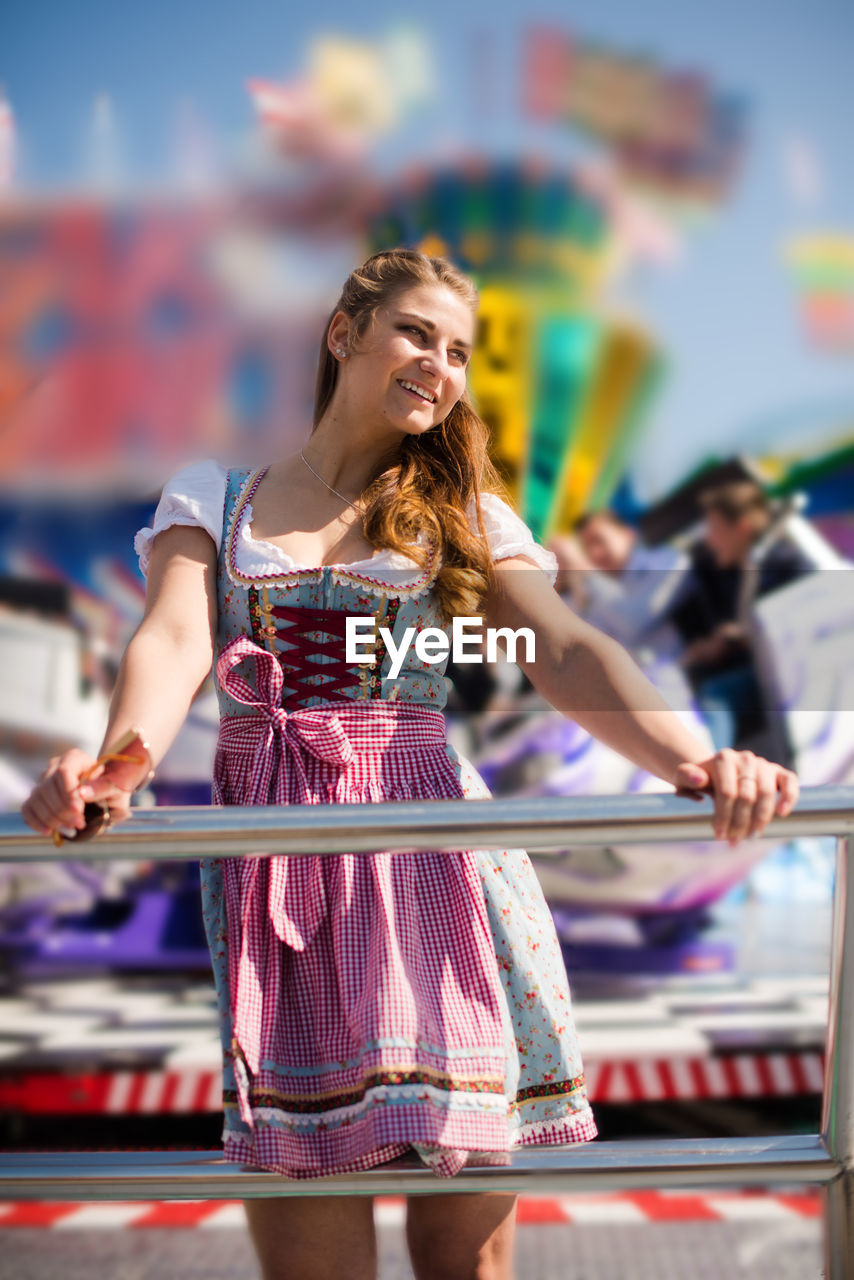 Smiling young woman standing at amusement park