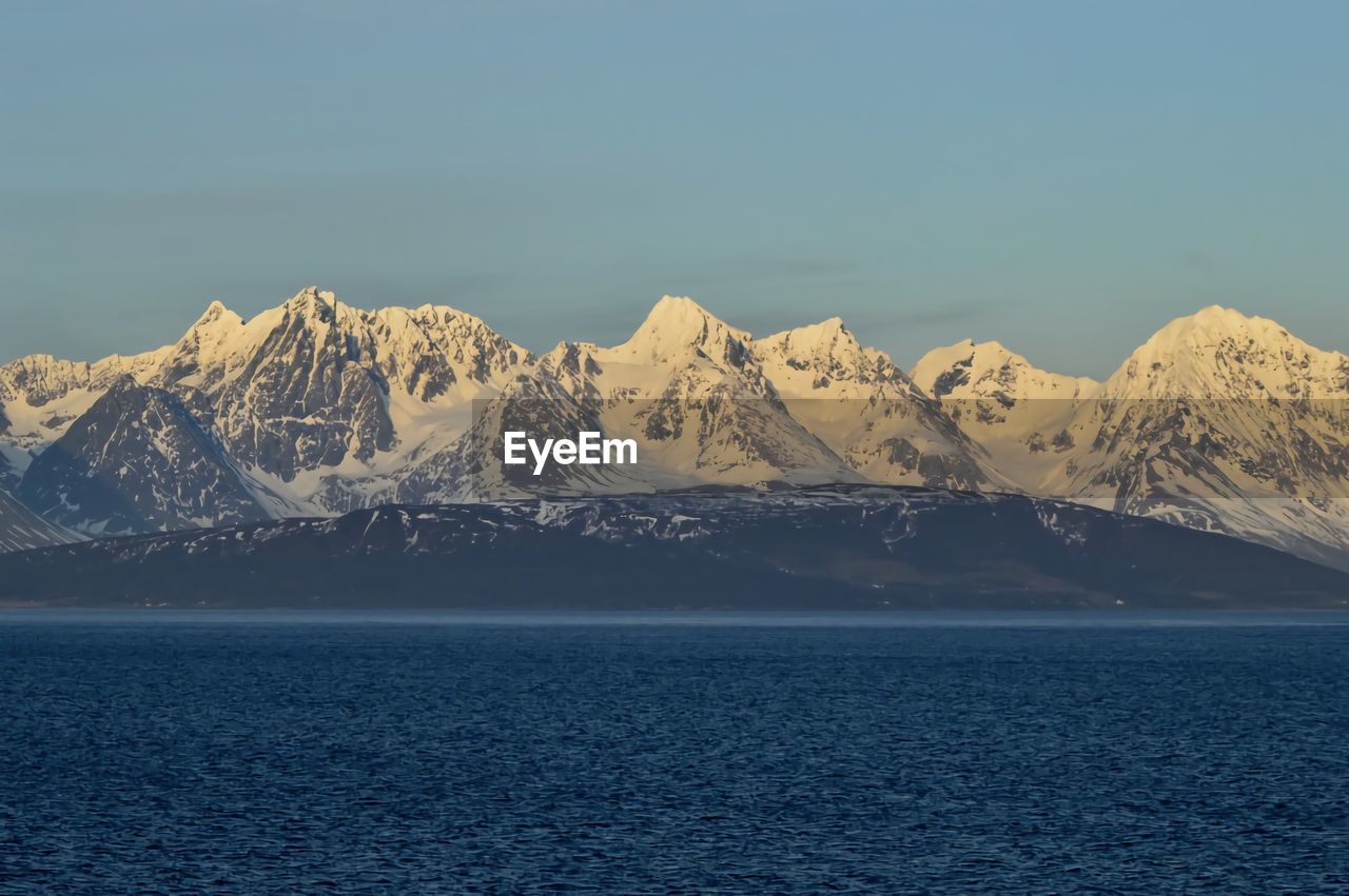 Scenic view of snowcapped mountains by sea against sky