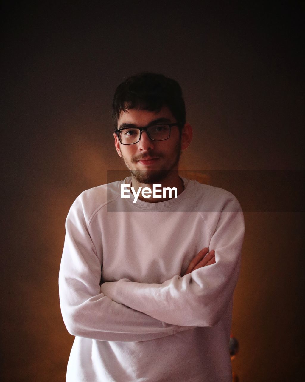 Portrait of young man standing against black background