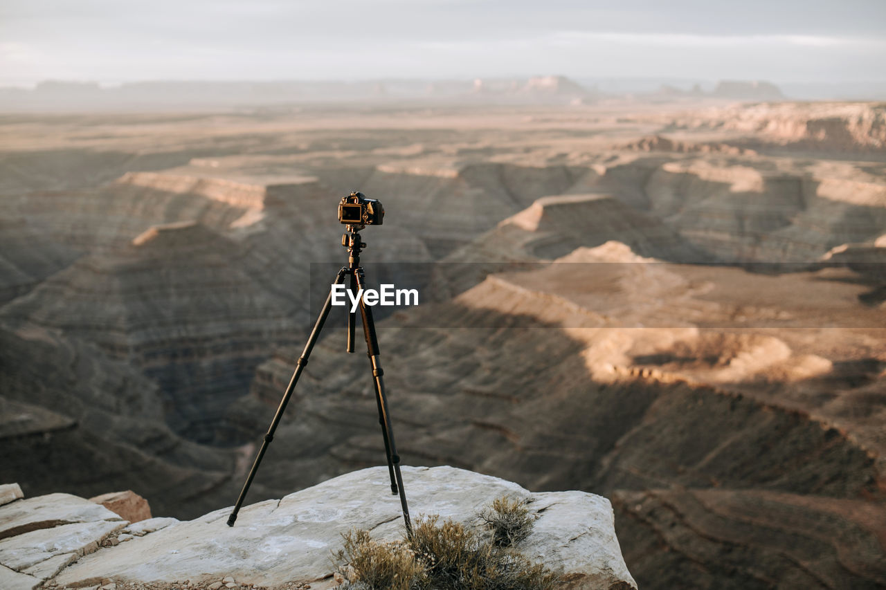Camera and tripod on cliff edge in front of scenic view, utah desert