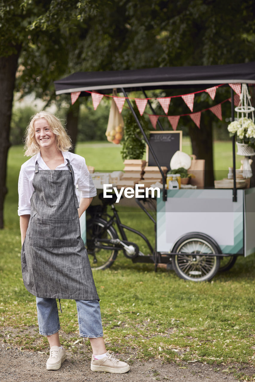 Smiling woman looking at camera, food stall on background