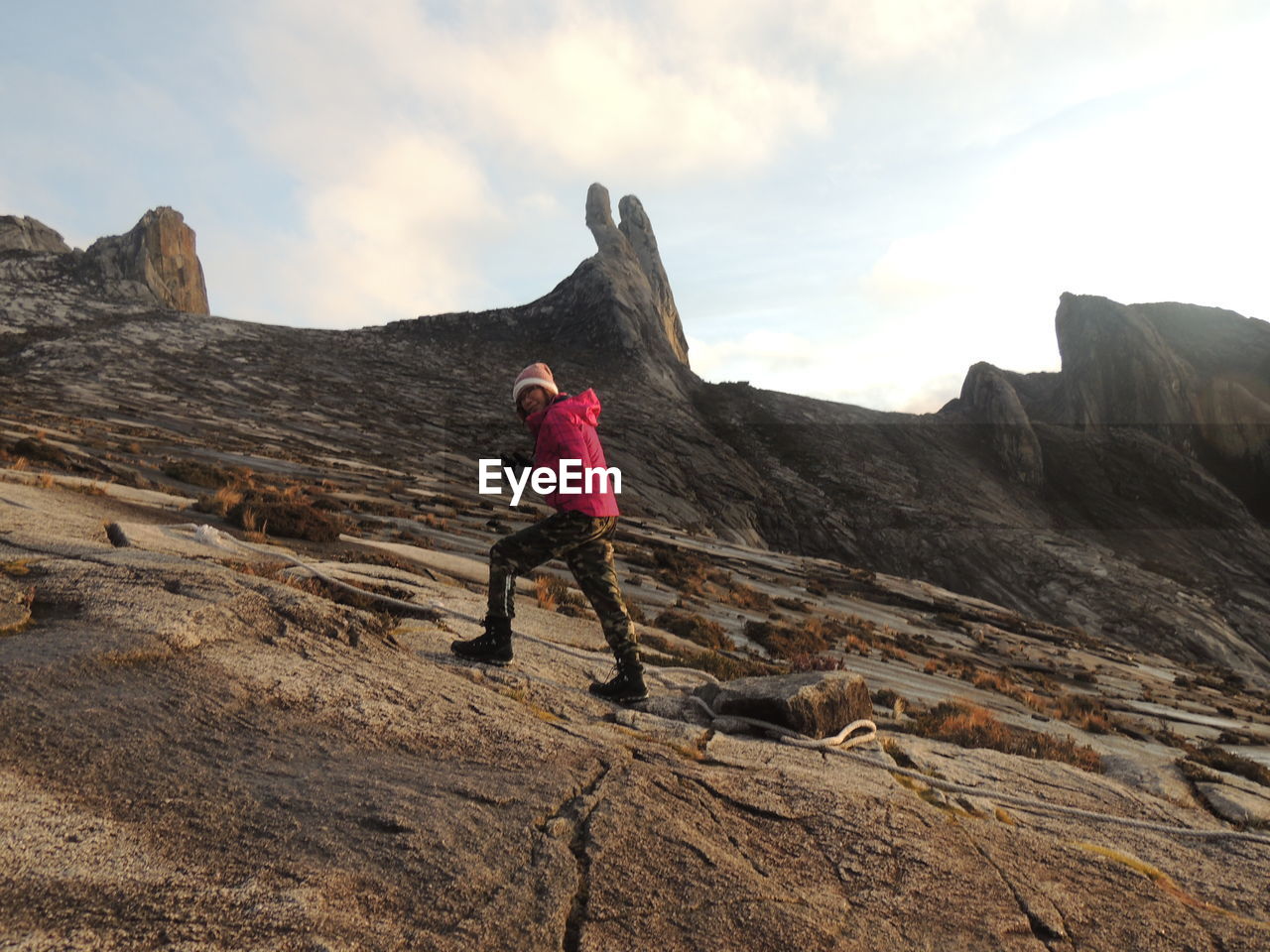 MAN STANDING ON ROCK FORMATION AGAINST SKY