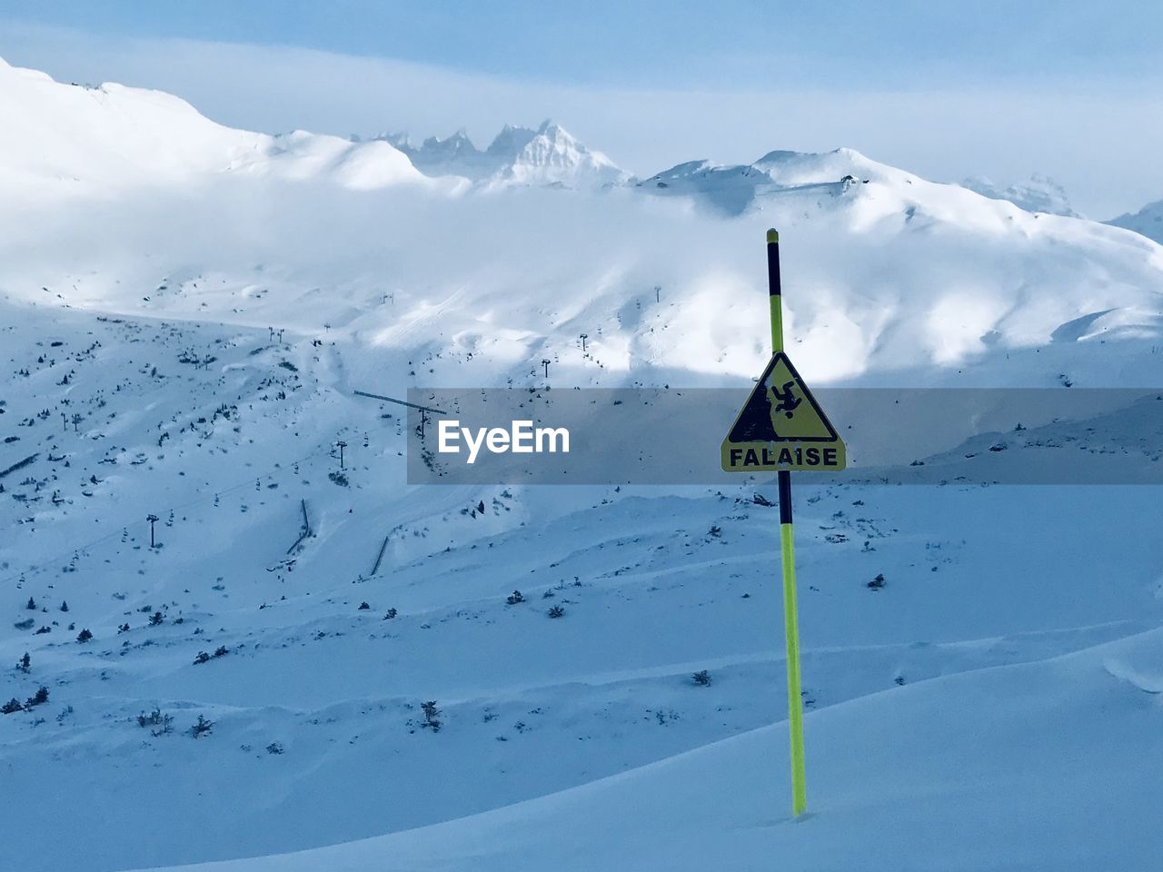 Scenic view of snow covered mountain against sky and warning sign