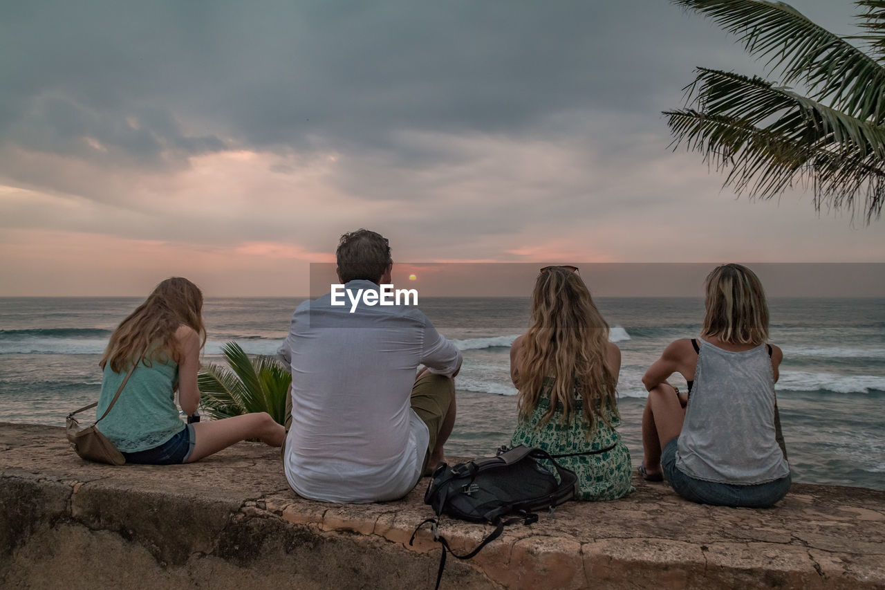 People sitting at beach against sky