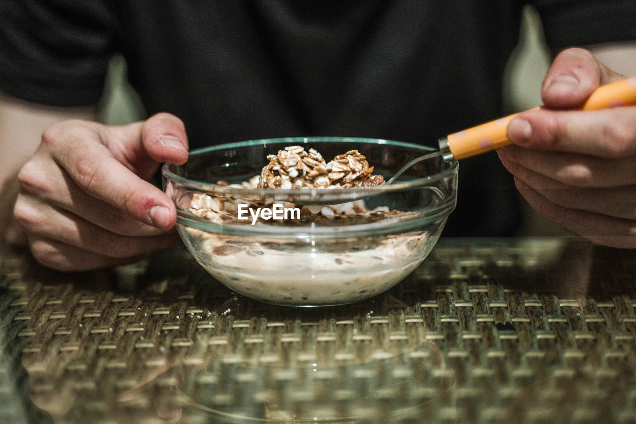 Man-eating cornflakes with milk on a wooden background.