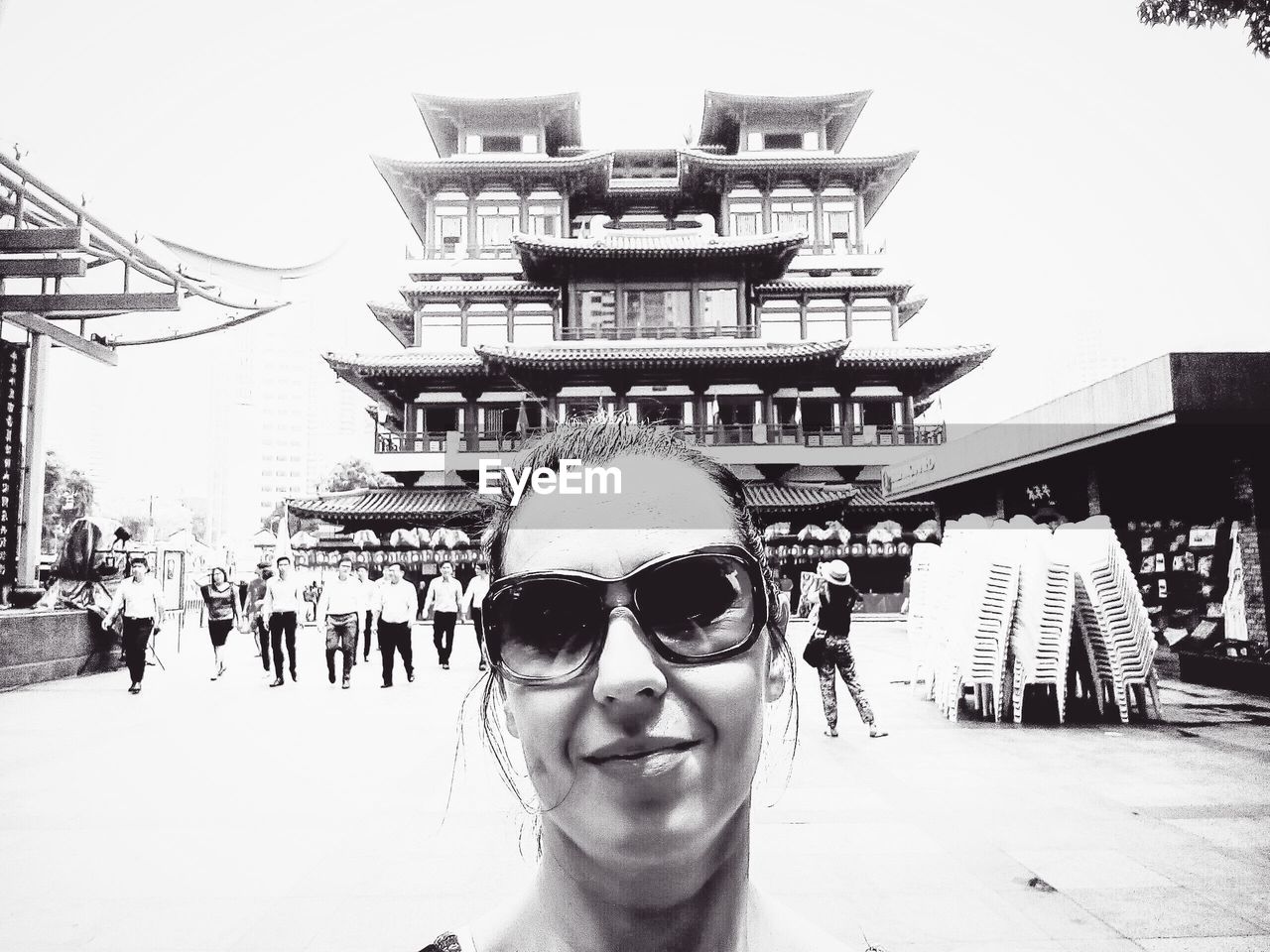 PORTRAIT OF SMILING YOUNG WOMAN AGAINST BUILDINGS