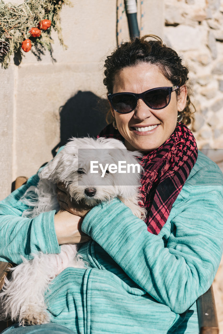 Portrait of dog and woman wearing sunglasses at home