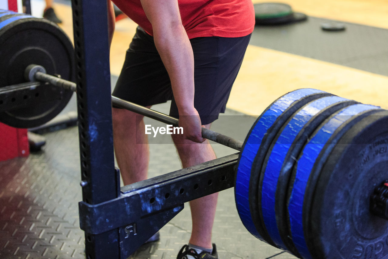 Mid section of a man exercising with barbell