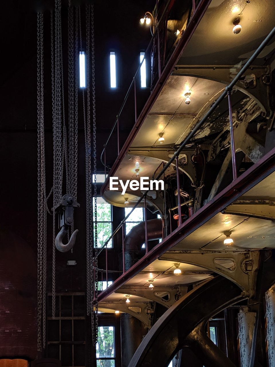 Low angle view of illuminated lights hanging from ceiling in industrial facility