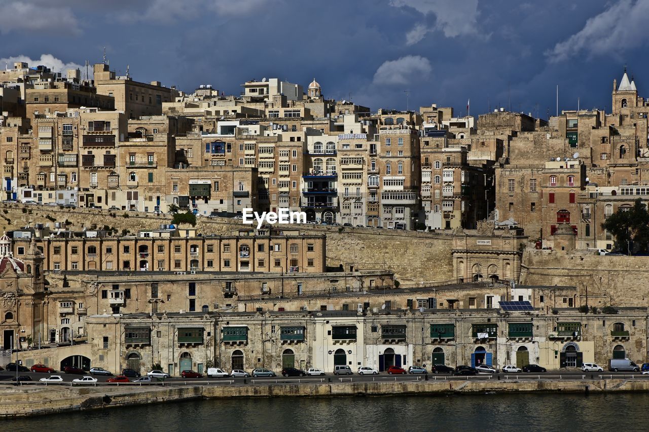 Built structures against the sky with river in foreground