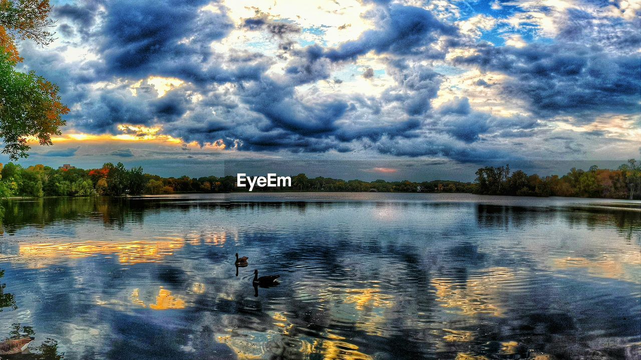 SCENIC VIEW OF LAKE AGAINST CLOUDY SKY AT SUNSET