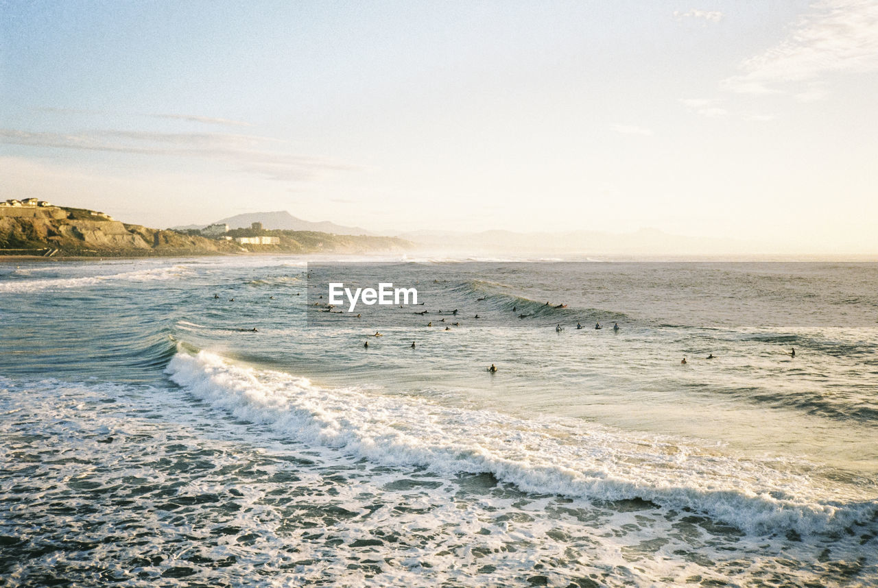 Surfers during sunset in biarritz, france. shot on 35mm kodak gold 200 film.