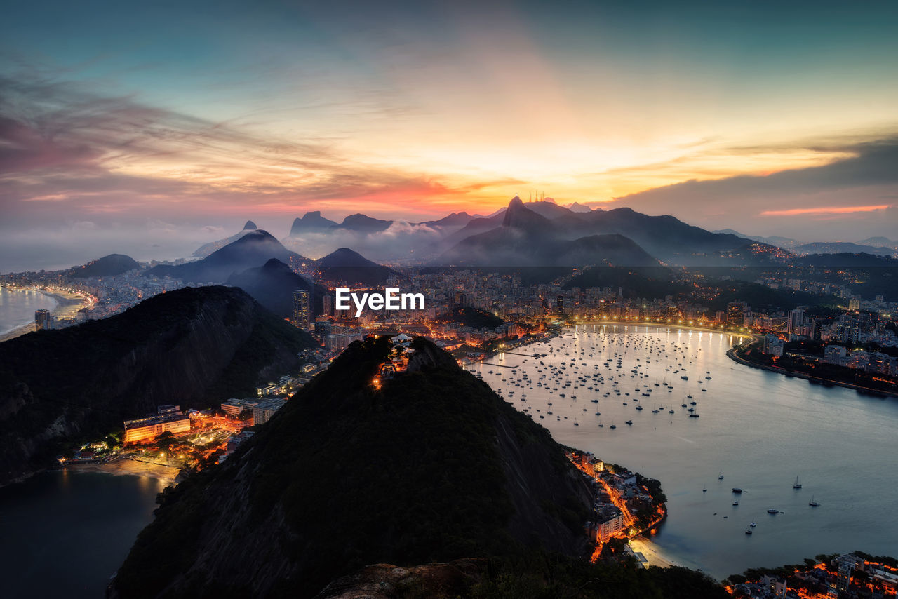 Aerial view of illuminated city against sky during sunset