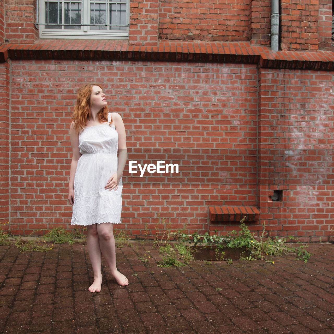 Thoughtful young woman standing against building