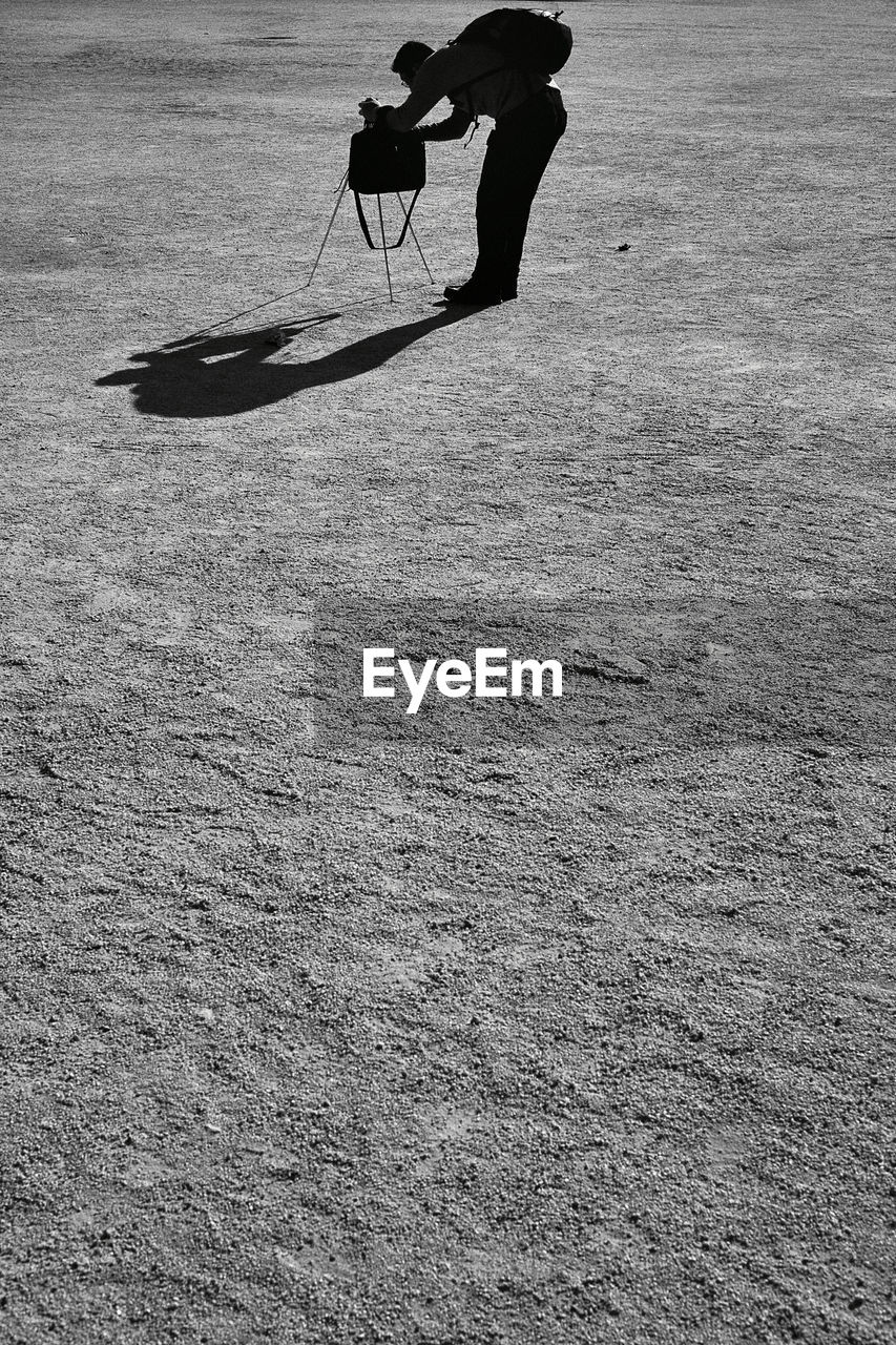 Side view of silhouette man photographing on land during sunny day