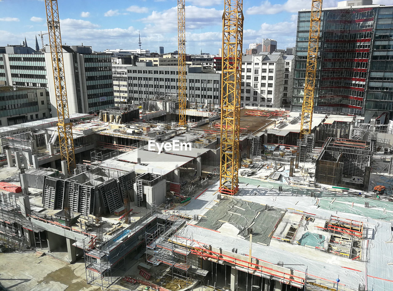 HIGH ANGLE VIEW OF CONSTRUCTION SITE AGAINST BUILDINGS