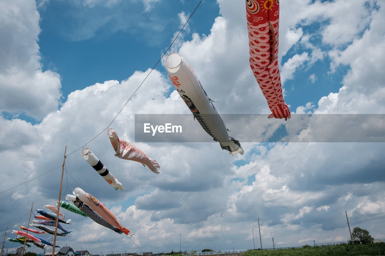 Low angle view of fish streamers hanging against sky