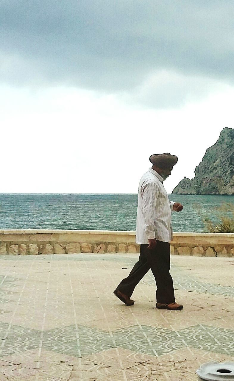 SIDE VIEW OF MAN ON SHORE AGAINST SEA