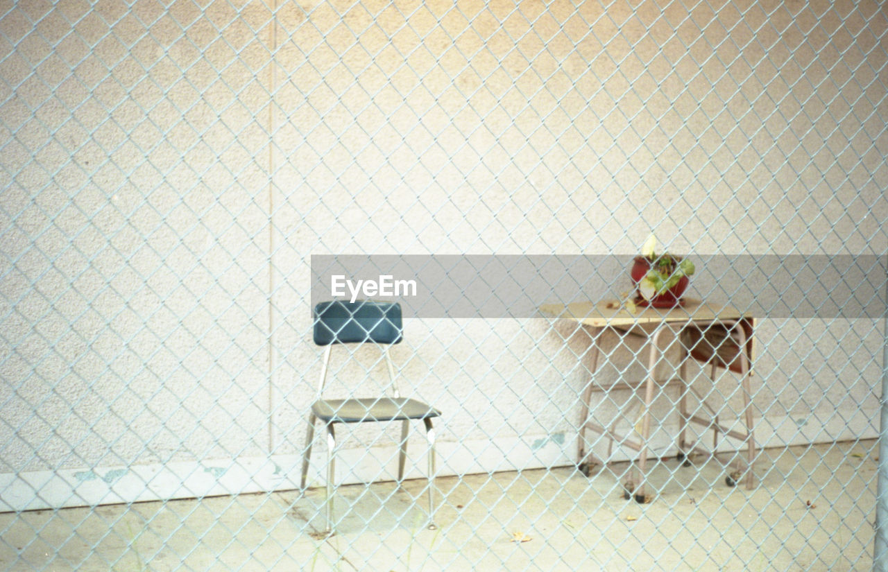 View of a chair and a desk with a dying plant behind a fence on a school campus in echo park, ca