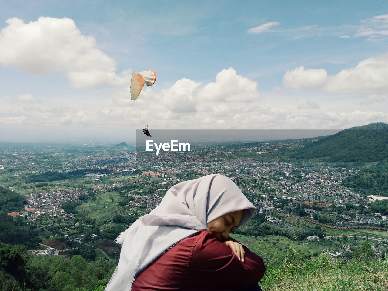 Rear view of man flying over cityscape against sky