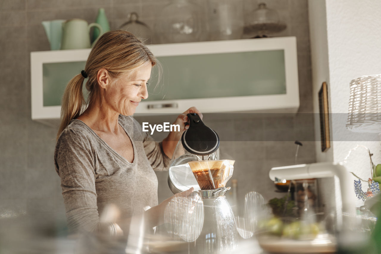 Woman at home in kitchen preparing coffee