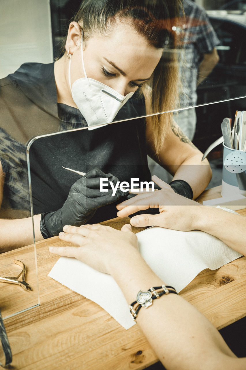 Beautician working with mask and protective screen for the virus covid