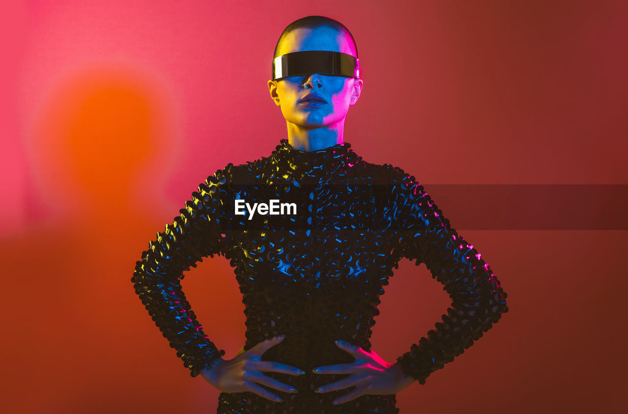 Woman wearing eyeglasses standing against red background