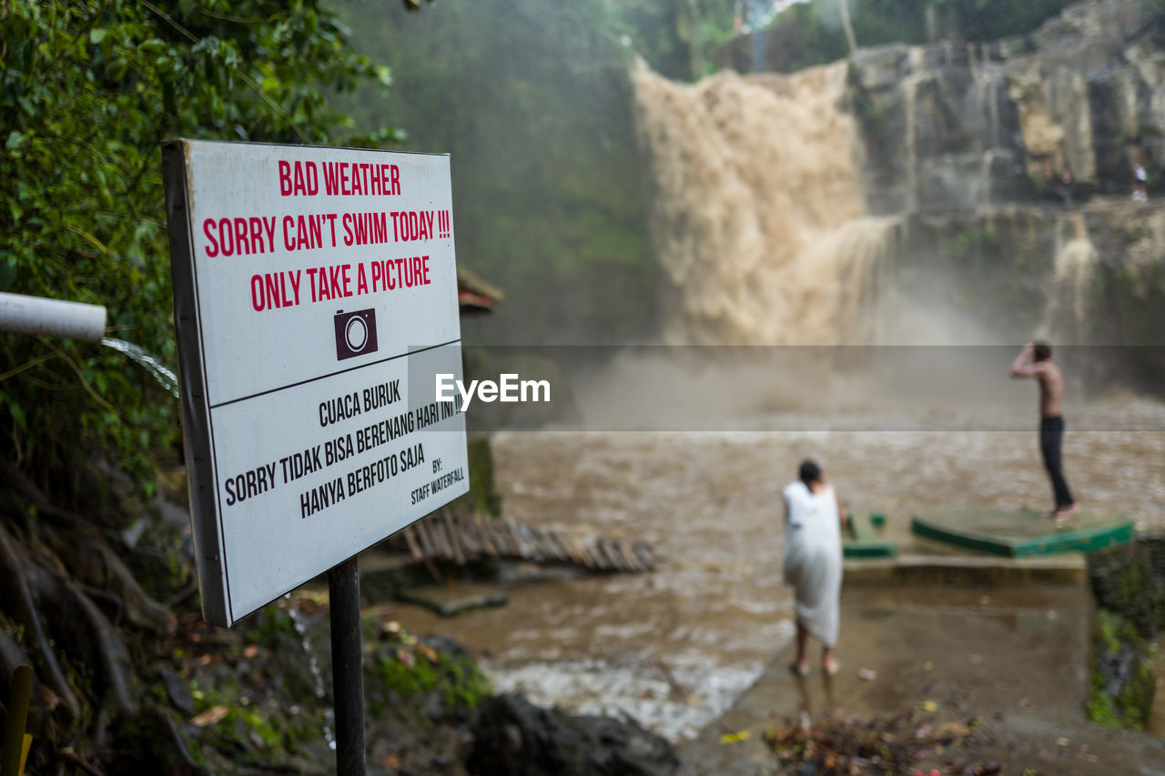 Close-up of signboard against waterfall