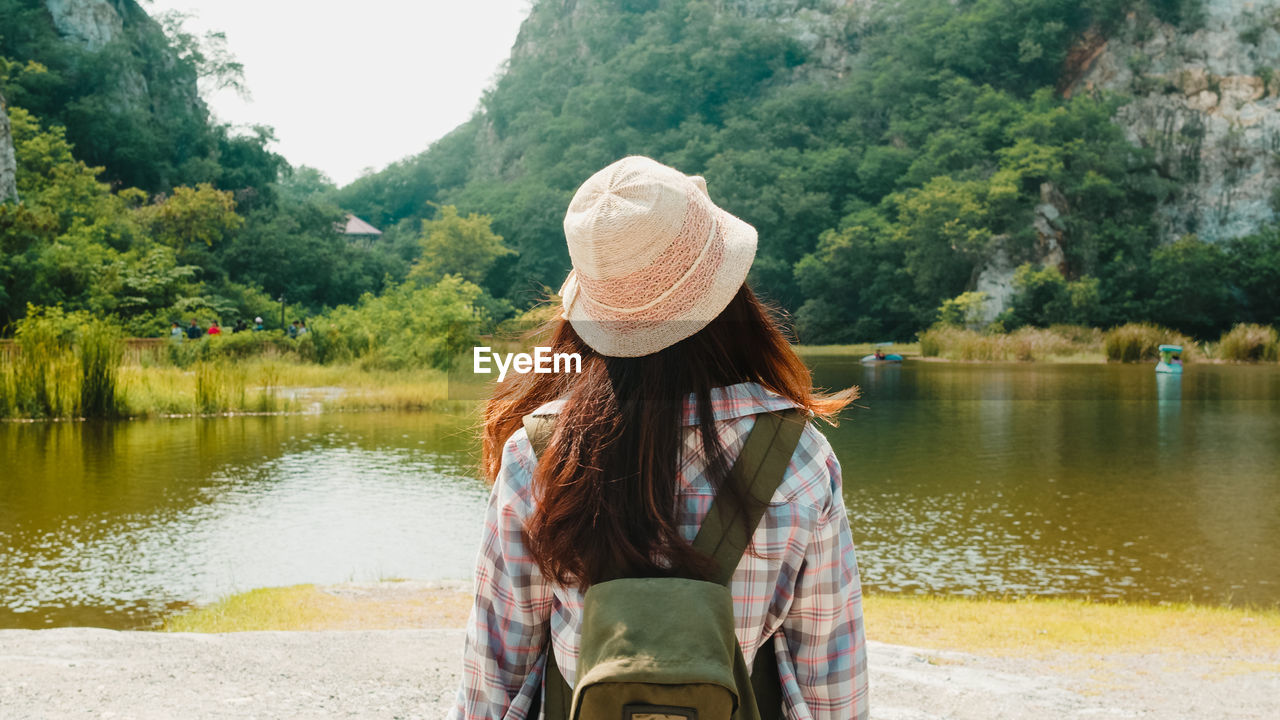 Woman looking at lake against trees