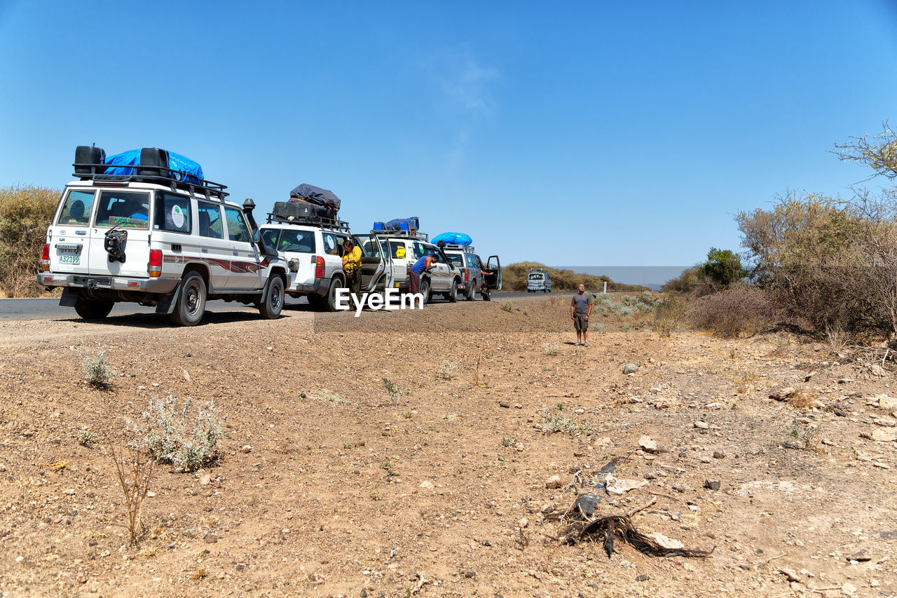 VIEW OF VEHICLES ON LAND AGAINST CLEAR BLUE SKY
