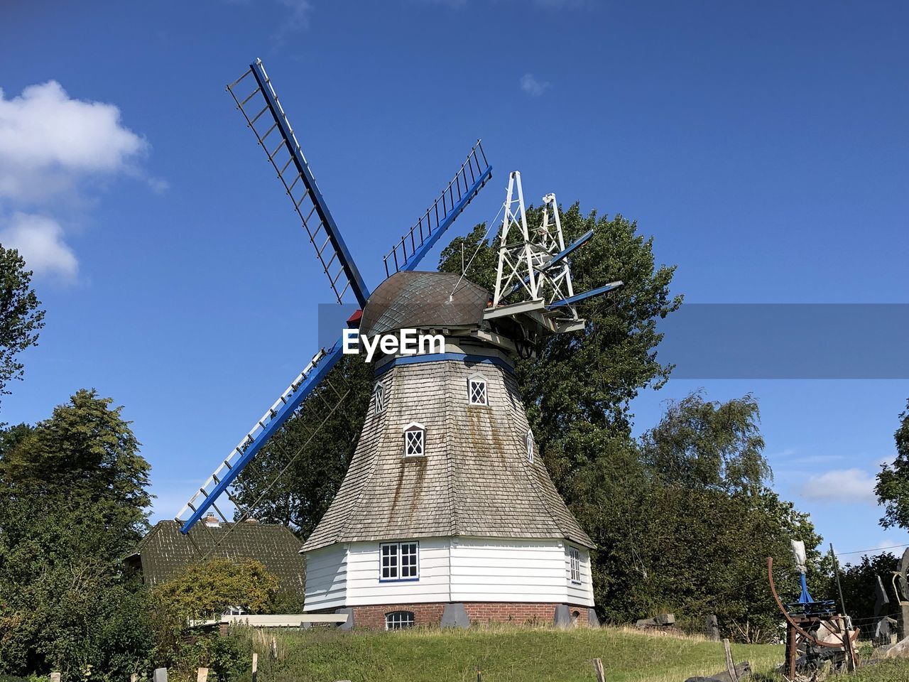 LOW ANGLE VIEW OF TRADITIONAL WINDMILL AGAINST TREES