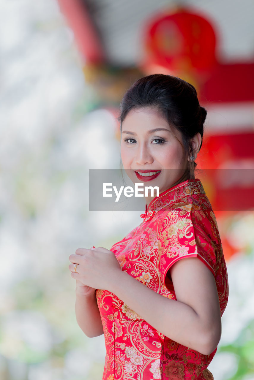 PORTRAIT OF SMILING YOUNG WOMAN OUTDOORS