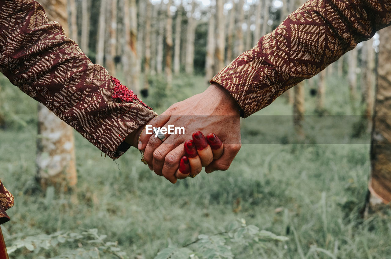 Cropped image of couple holding hands in forest