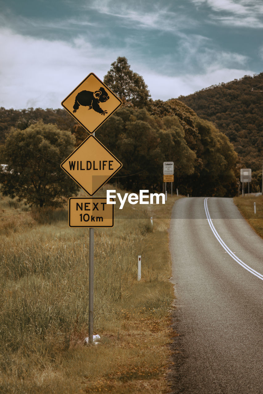 Information sign by road against sky