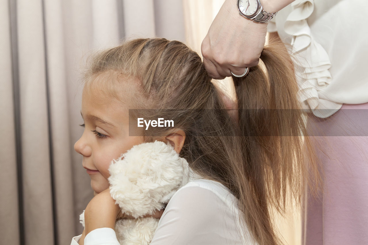 Midsection of mother tying daughter hair