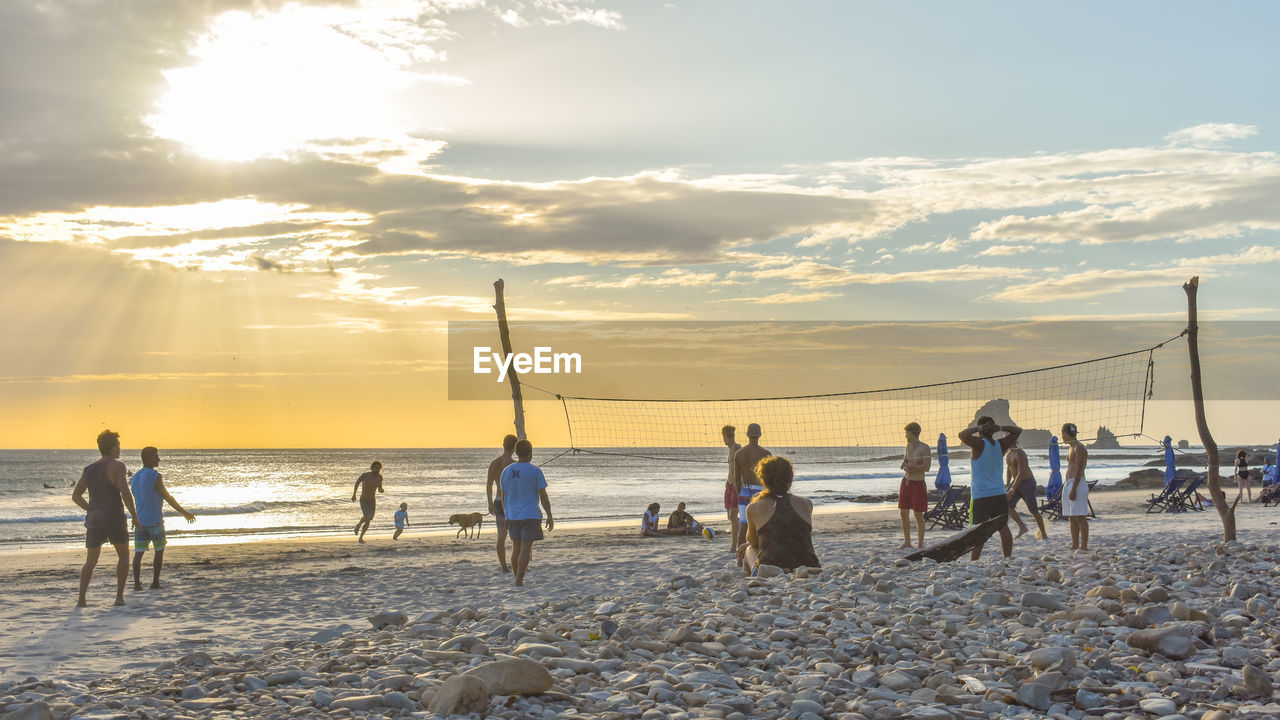 People on beach against sky during sunset