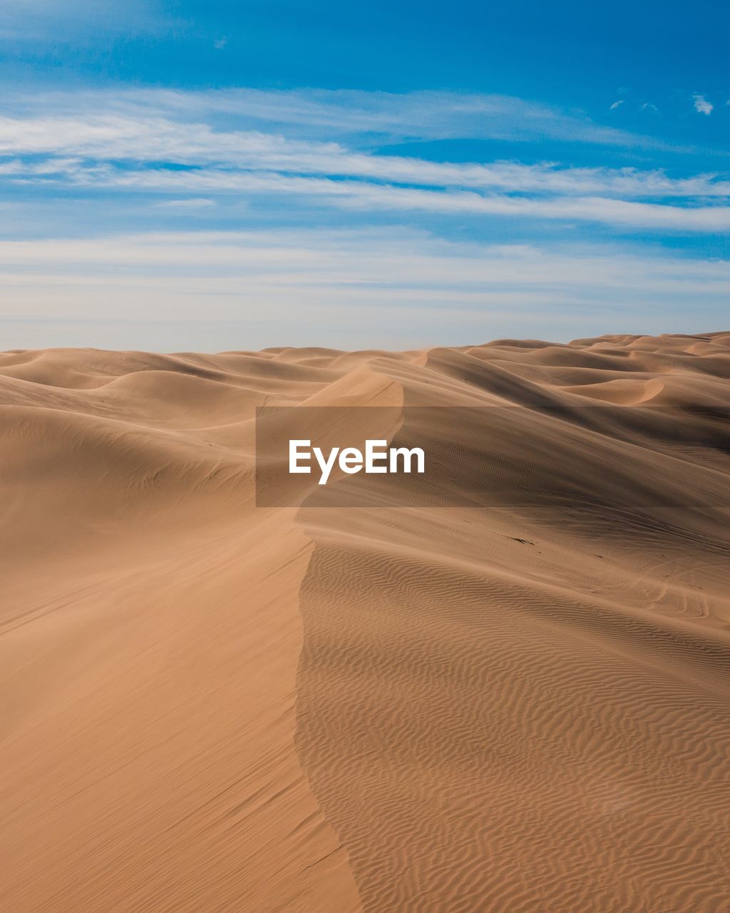 Scenic view of desert dunes against blue sky