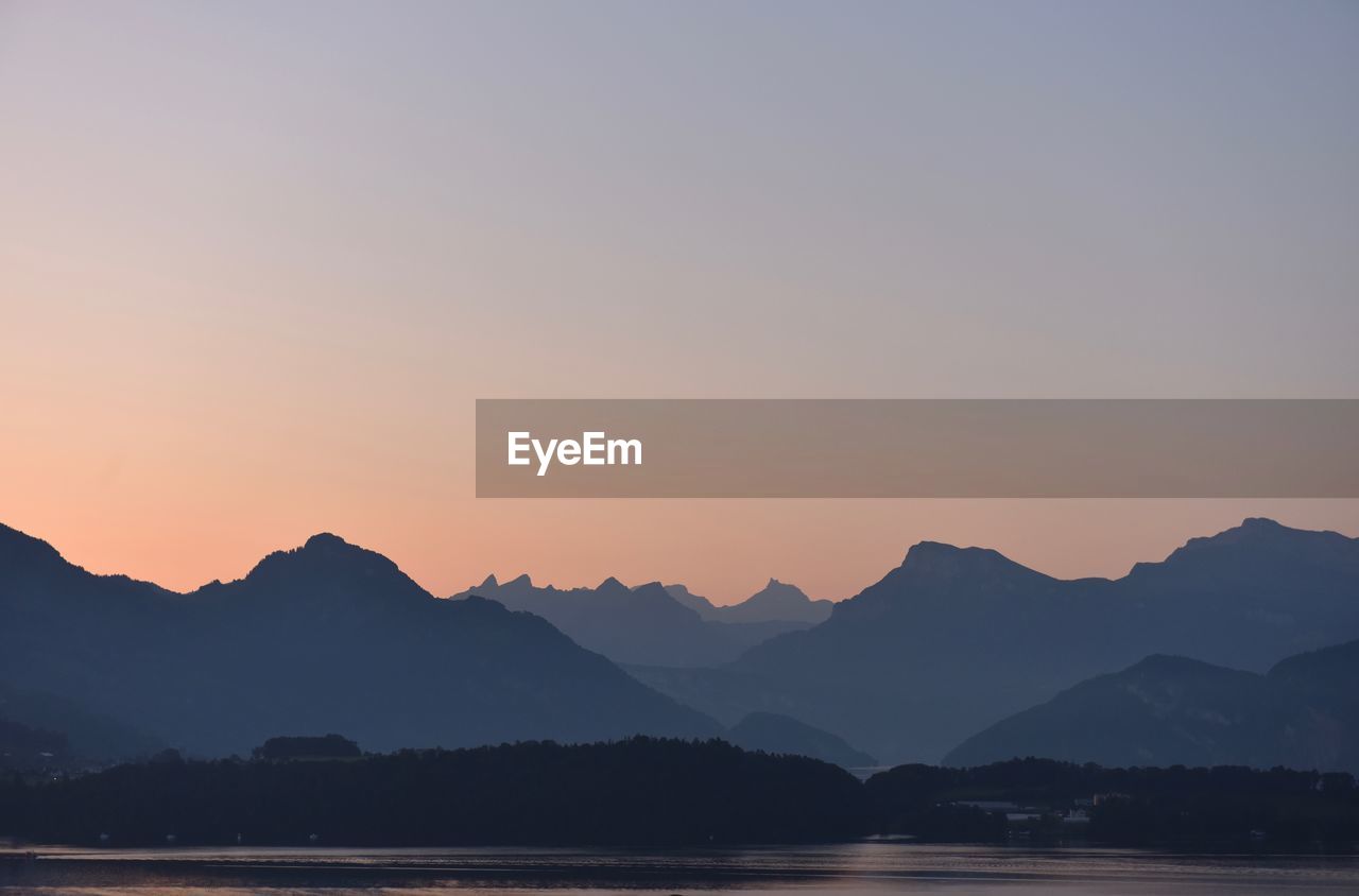 SILHOUETTE MOUNTAINS AGAINST ROMANTIC SKY AT SUNSET